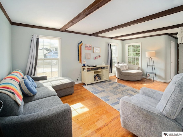 living room with beam ceiling, crown molding, baseboards, and light wood finished floors