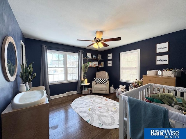 bedroom with a ceiling fan, wood finished floors, visible vents, and baseboards