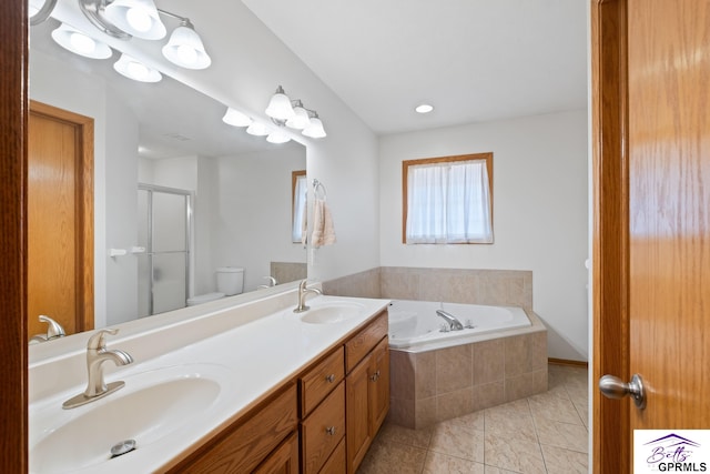 bathroom featuring double vanity, a shower stall, a garden tub, and a sink