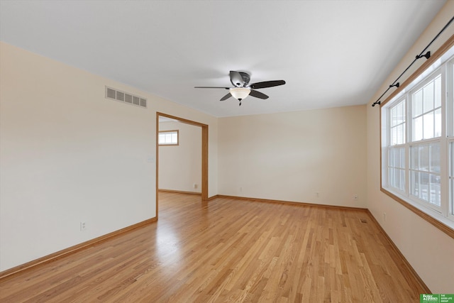 unfurnished room featuring a ceiling fan, light wood-style flooring, baseboards, and visible vents