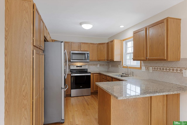 kitchen featuring a sink, a peninsula, backsplash, and stainless steel appliances