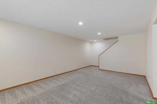 spare room featuring recessed lighting, light colored carpet, and baseboards