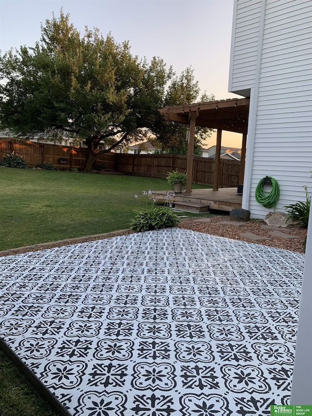 yard at dusk featuring a deck and fence