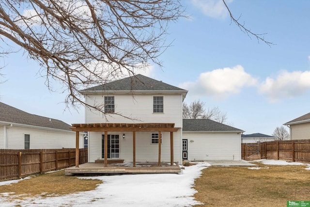 snow covered property with a shingled roof, a yard, a fenced backyard, and a wooden deck