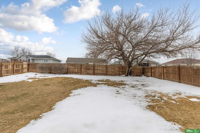 snowy yard featuring a fenced backyard