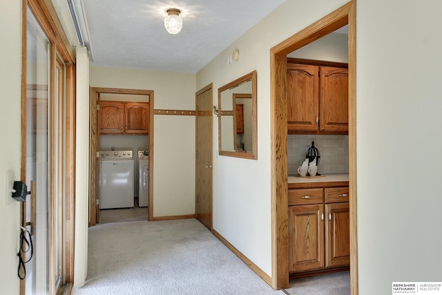 corridor with washer and dryer, visible vents, light colored carpet, and baseboards