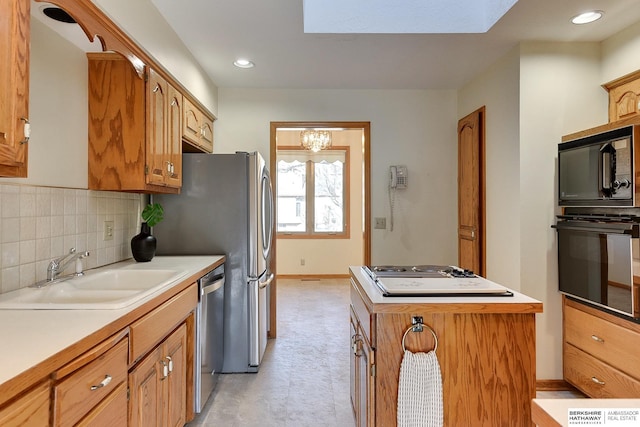 kitchen with a kitchen island, a sink, decorative backsplash, black appliances, and light countertops