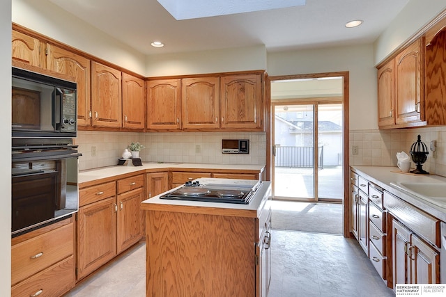 kitchen with black appliances, a center island, and light countertops