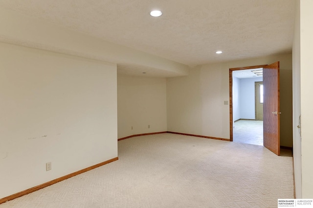 spare room with a textured ceiling, recessed lighting, baseboards, and light carpet