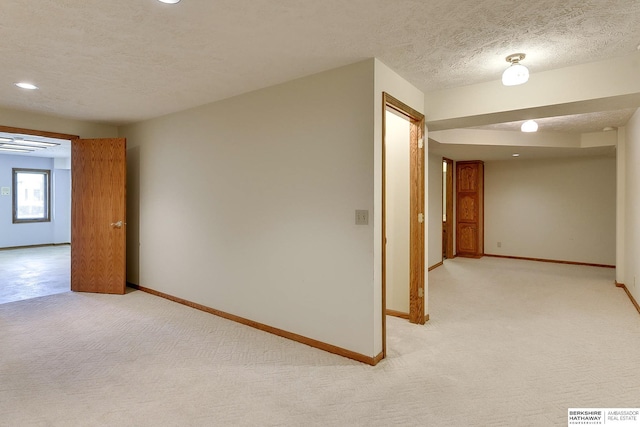 unfurnished room with baseboards, light carpet, a textured ceiling, and visible vents