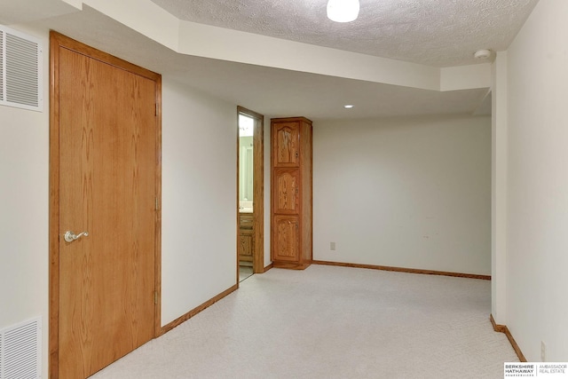 unfurnished room featuring light carpet, visible vents, a textured ceiling, and baseboards