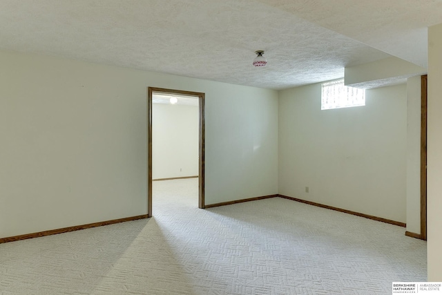 carpeted empty room featuring baseboards and a textured ceiling