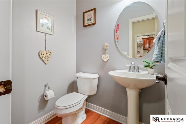 bathroom with toilet, wood finished floors, and baseboards