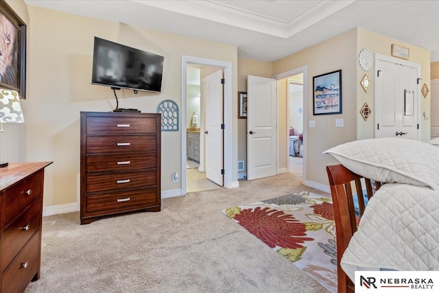 bedroom featuring crown molding, baseboards, light carpet, ensuite bathroom, and a raised ceiling