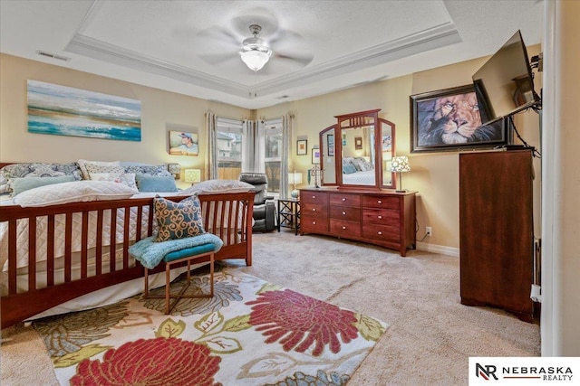 bedroom with visible vents, baseboards, a tray ceiling, light carpet, and a ceiling fan