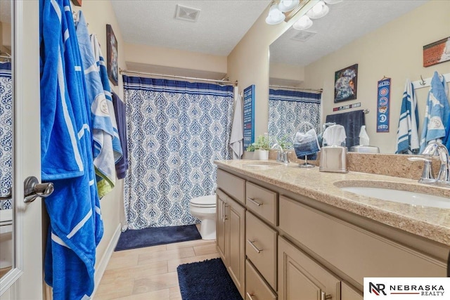 bathroom featuring a textured ceiling, toilet, visible vents, and a sink