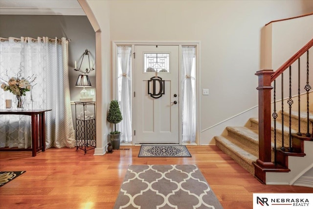 foyer featuring stairway, arched walkways, and wood finished floors