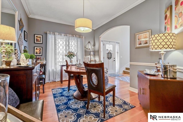 dining room with crown molding, wood finished floors, and arched walkways