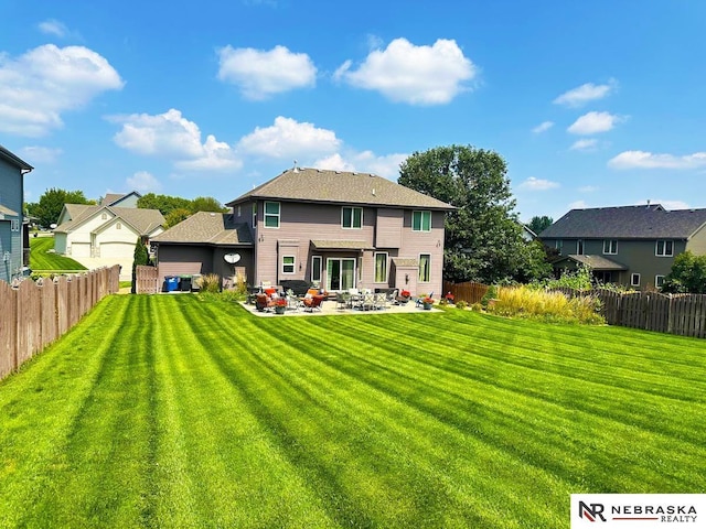 rear view of house with a fenced backyard, a residential view, a lawn, and a patio