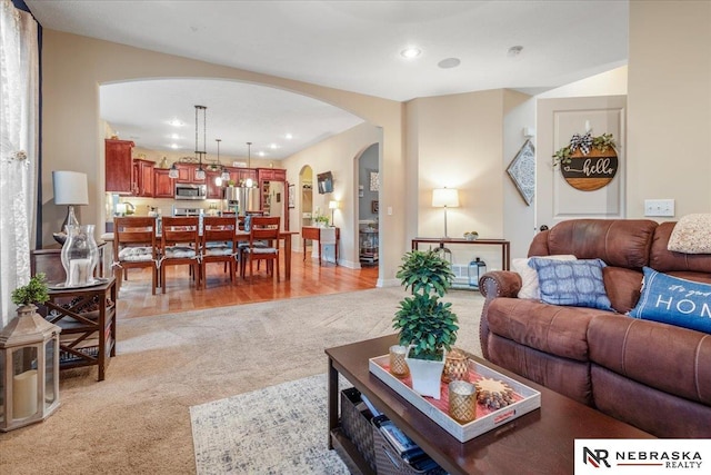 living room featuring recessed lighting, arched walkways, and light colored carpet