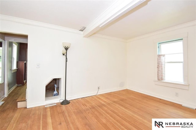 interior space featuring light wood finished floors, beam ceiling, baseboards, and ornamental molding