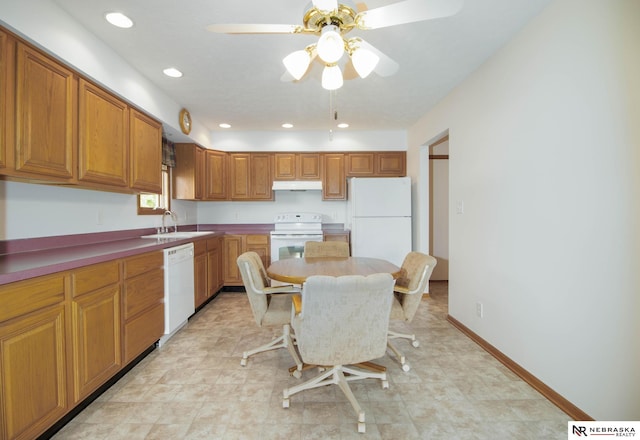 kitchen featuring white appliances, baseboards, a sink, under cabinet range hood, and brown cabinets