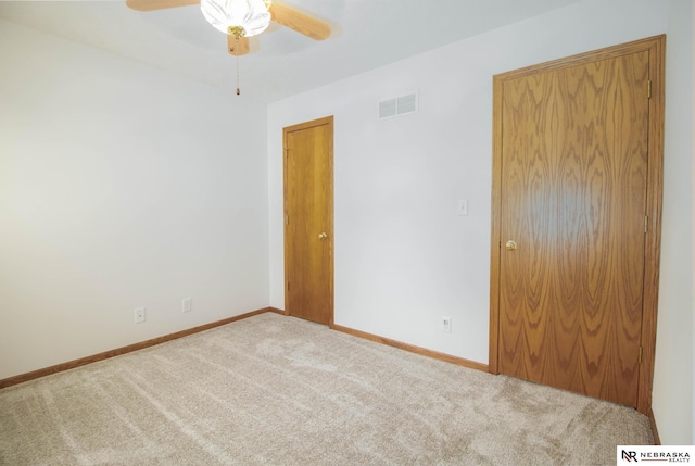 carpeted empty room featuring visible vents, baseboards, and a ceiling fan