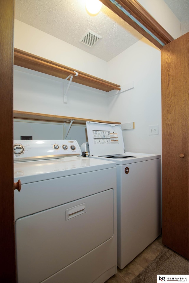 washroom with washer and dryer, visible vents, a textured ceiling, and laundry area