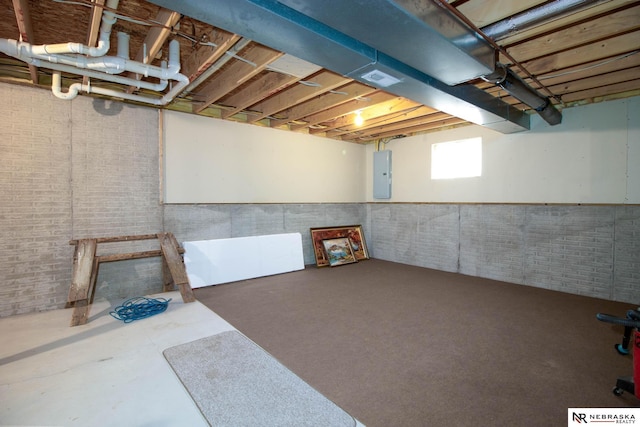 basement featuring electric panel and brick wall