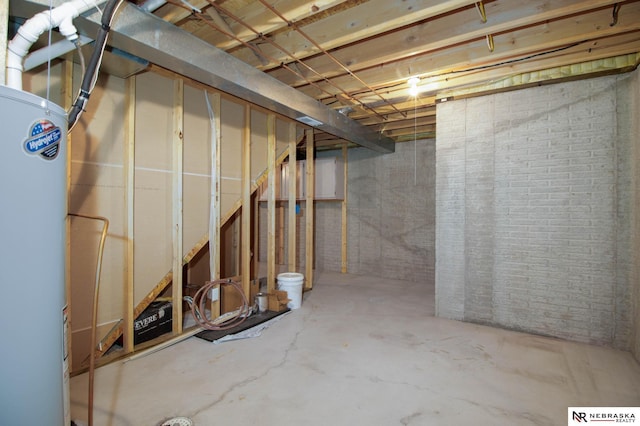 unfinished basement featuring water heater and brick wall