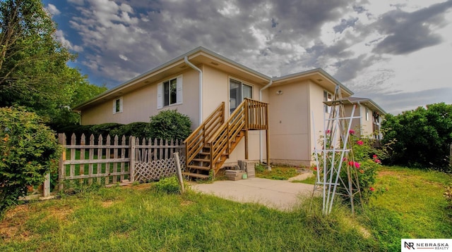 rear view of house with a patio area, fence, and stucco siding