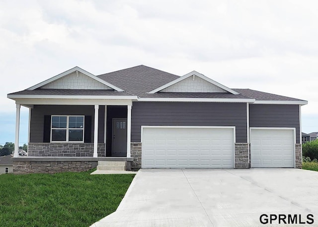 view of front of house with a shingled roof, a front lawn, a garage, stone siding, and driveway