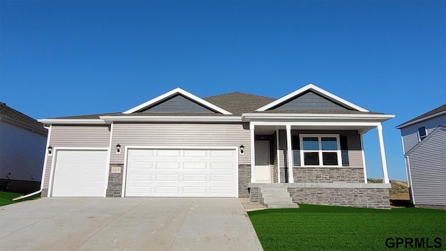 view of front of home with stone siding, an attached garage, concrete driveway, and a front lawn