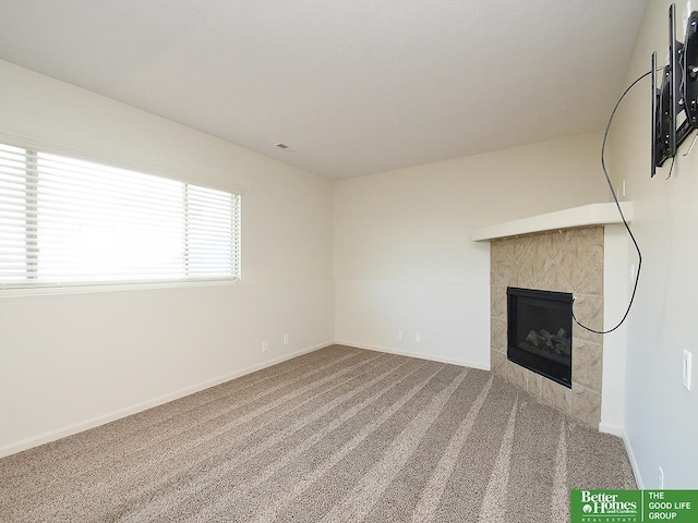 unfurnished living room featuring visible vents, carpet flooring, a fireplace, and baseboards