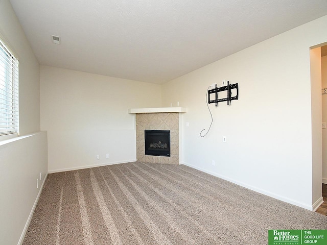 unfurnished living room featuring baseboards, carpet floors, visible vents, and a fireplace