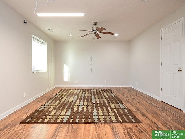 empty room featuring a ceiling fan, visible vents, wood finished floors, and baseboards