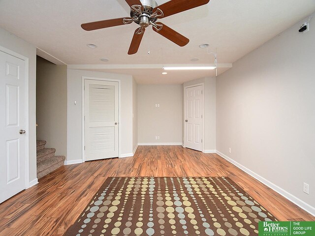 empty room featuring wood finished floors, baseboards, and ceiling fan