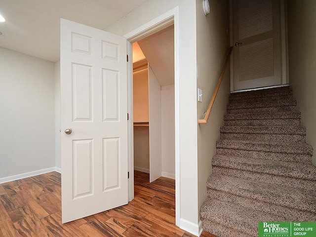 staircase featuring baseboards and wood finished floors