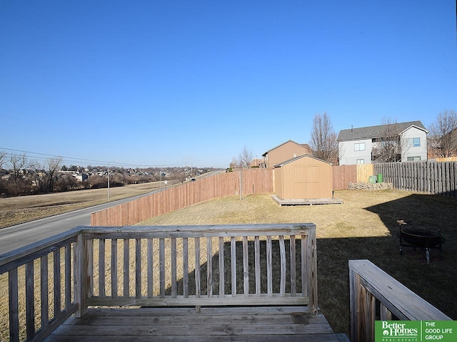 view of yard with a storage unit, a fenced backyard, a wooden deck, and an outdoor structure