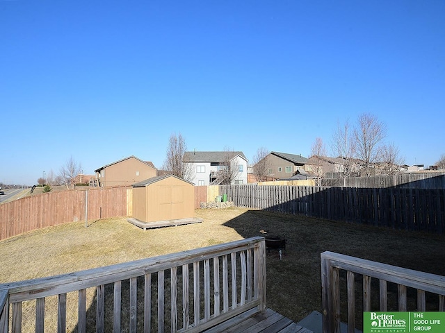 view of yard with a fenced backyard, a residential view, a storage shed, and an outdoor structure