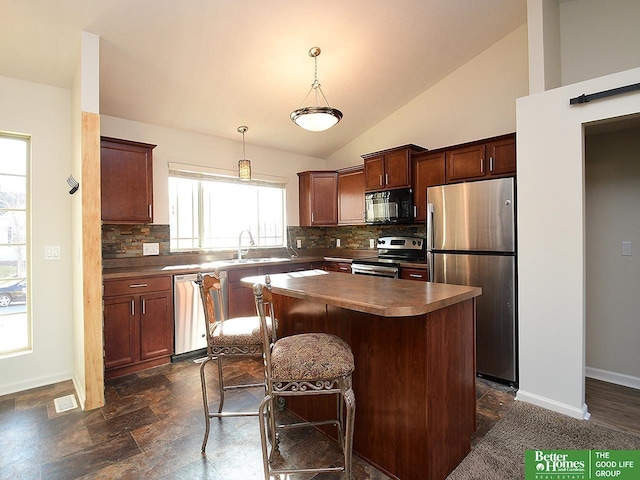 kitchen featuring baseboards, a kitchen island, a sink, decorative backsplash, and stainless steel appliances