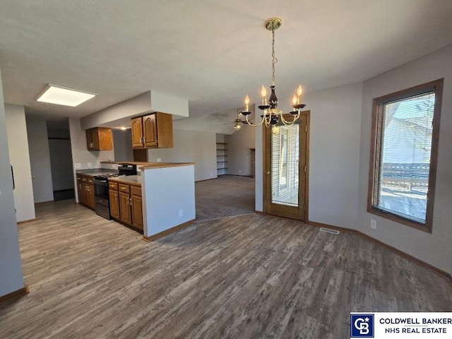 kitchen featuring a healthy amount of sunlight, black stove, open floor plan, brown cabinetry, and a notable chandelier