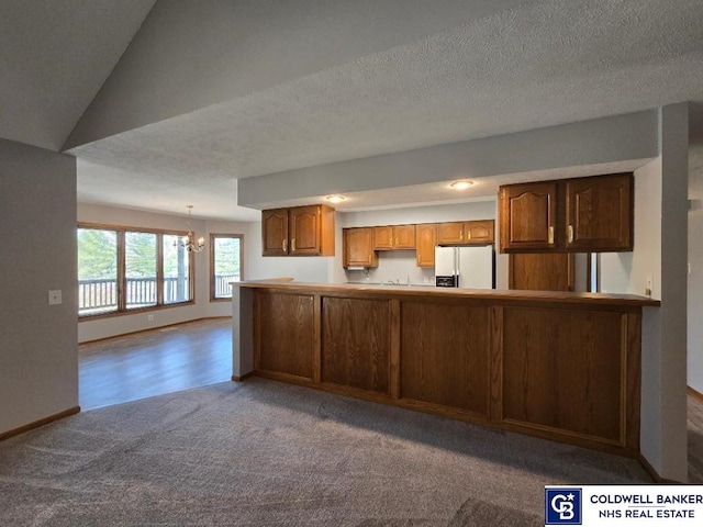 kitchen featuring baseboards, an inviting chandelier, white fridge with ice dispenser, a textured ceiling, and carpet flooring