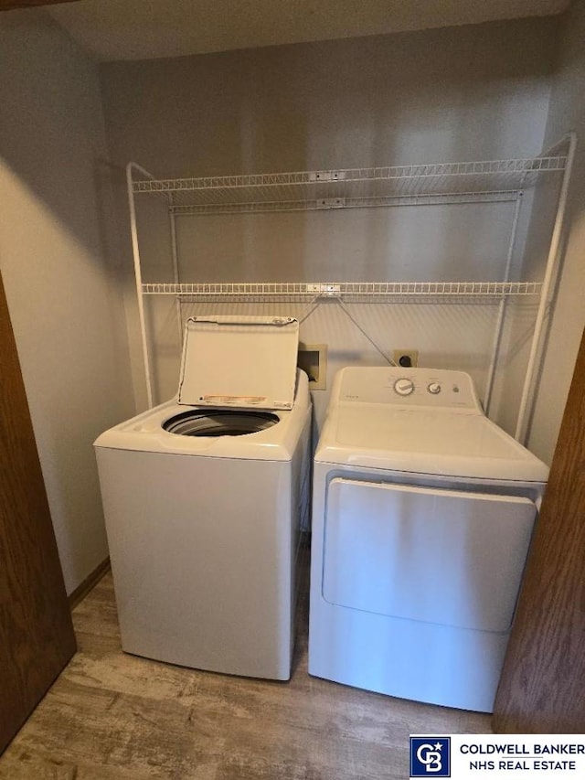 laundry area with laundry area, washer and dryer, and wood finished floors