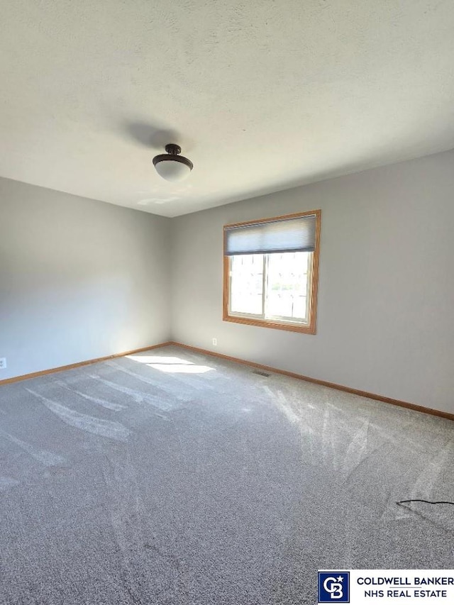 carpeted empty room featuring baseboards and a textured ceiling