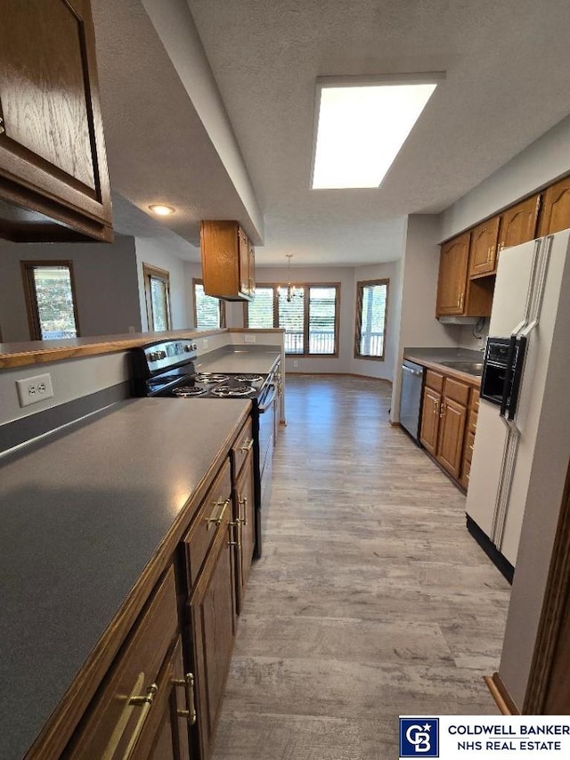 kitchen with electric range, light wood-style flooring, white fridge with ice dispenser, stainless steel dishwasher, and dark countertops