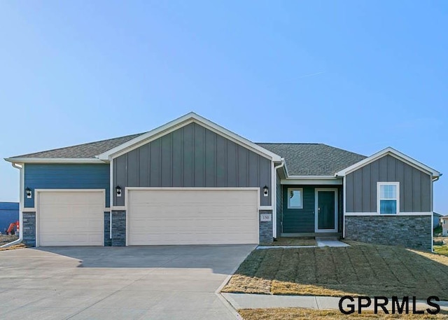 view of front of property featuring stone siding, an attached garage, concrete driveway, and board and batten siding