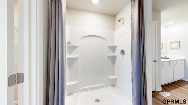 bathroom featuring visible vents, walk in shower, wood finished floors, and vanity