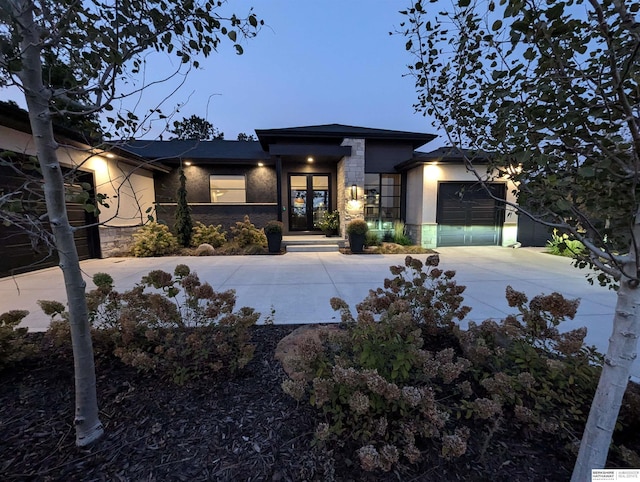 prairie-style house with concrete driveway, a garage, stone siding, and stucco siding