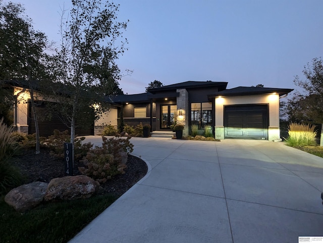 prairie-style home featuring a garage, driveway, and stucco siding